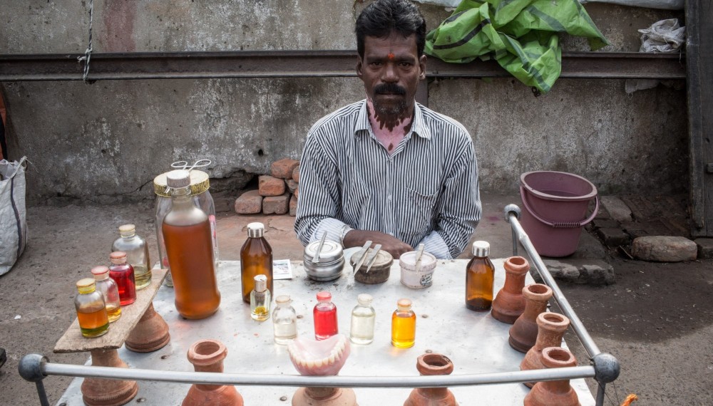 Kalkutta, West Bengalen: Ein
Straßenzahnarzt sitzt an seinem kleinen Laden. Er
behandelt die Zahnbeschwerden seiner Patienten mit verschiedenen Ölen und einer
Rauchtherapie. Das soll Infektionen stoppen und Schmerz lindern. Der Mann lernte
dieses Handwerk von seinem Vater.